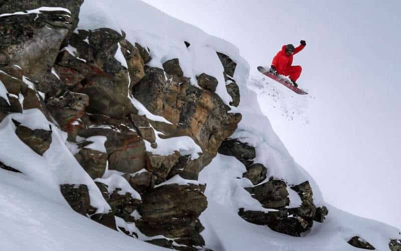 snowboarder getting air going over a cliff